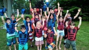 kids posing for a group photo wearing red and blue z tag standing in a backyard on the grass